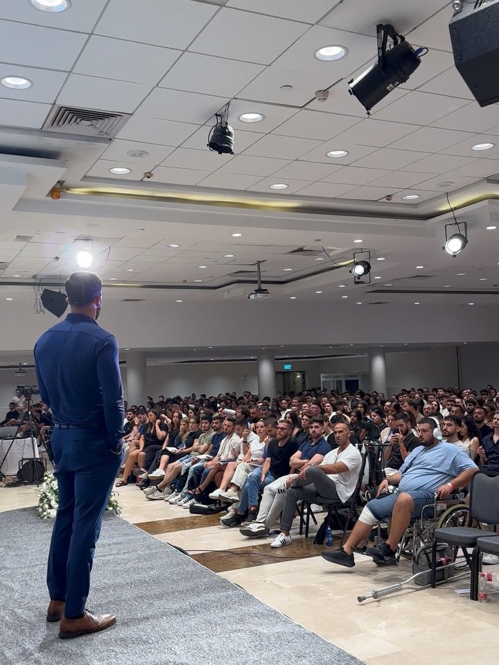 Marczell Klein on stage speaking to a packed audience