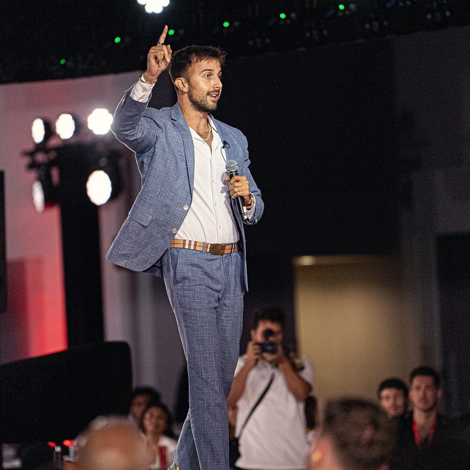 Marczell Klein in a blue suit, pointing upward while he talks.
