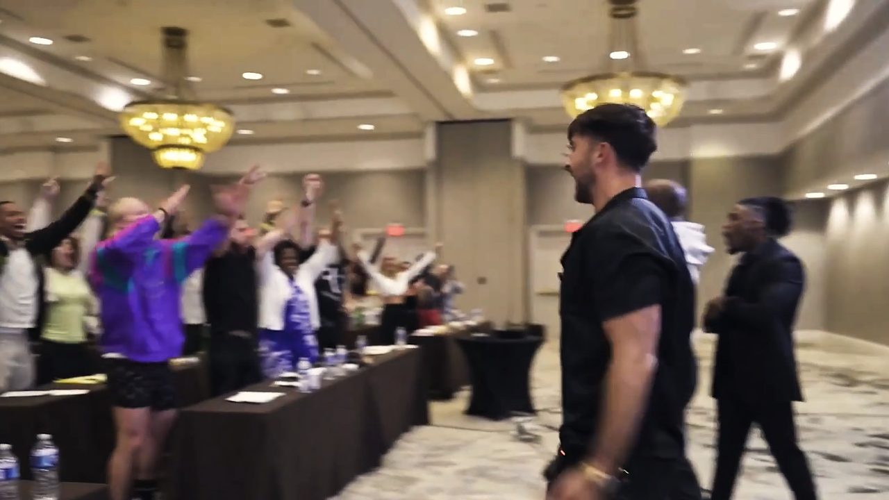 Marczell Klein walking through a seminar room while the audience stands.