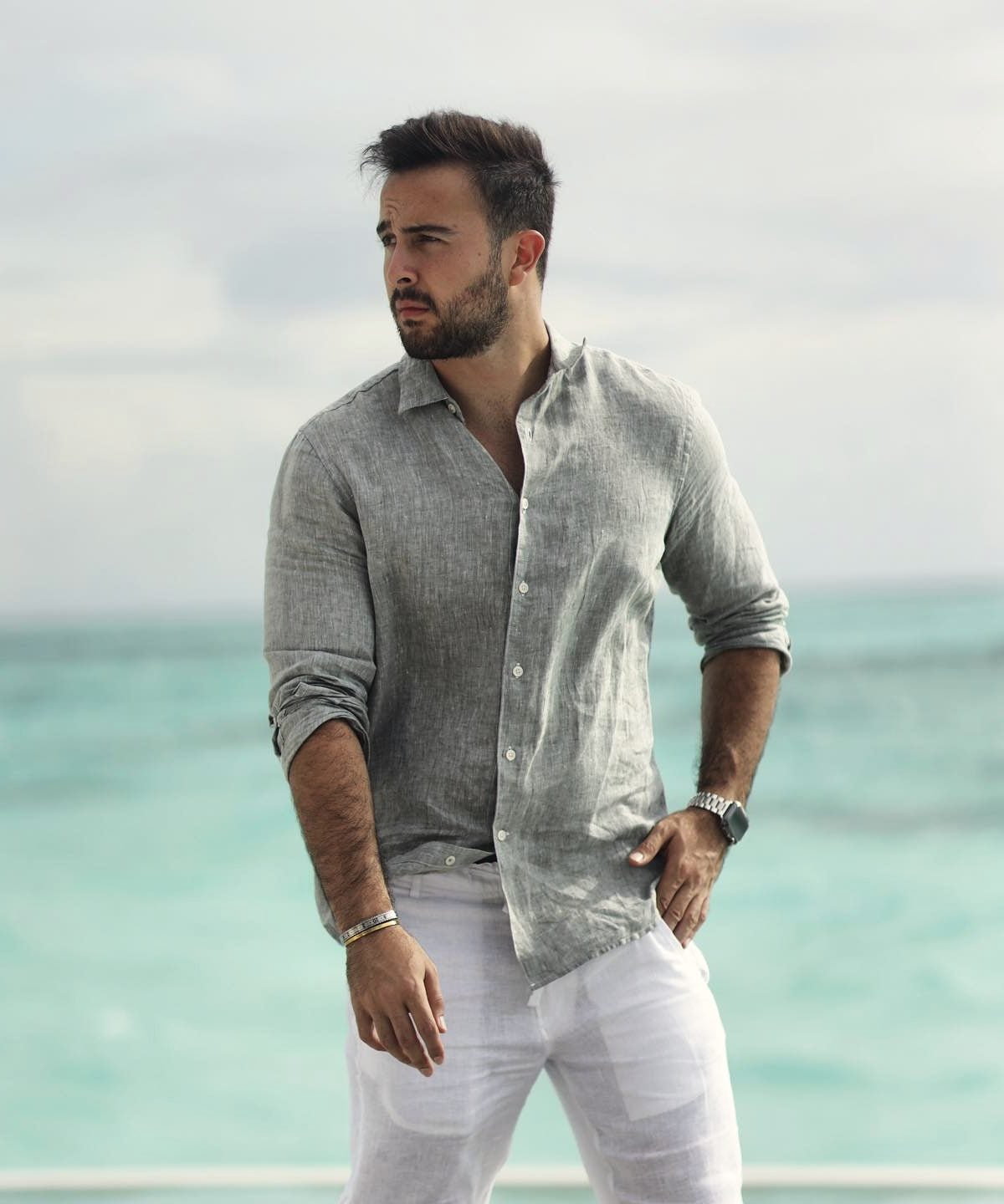 Marczell Klein in a linen shirt standing at the edge of a turquoise sea.