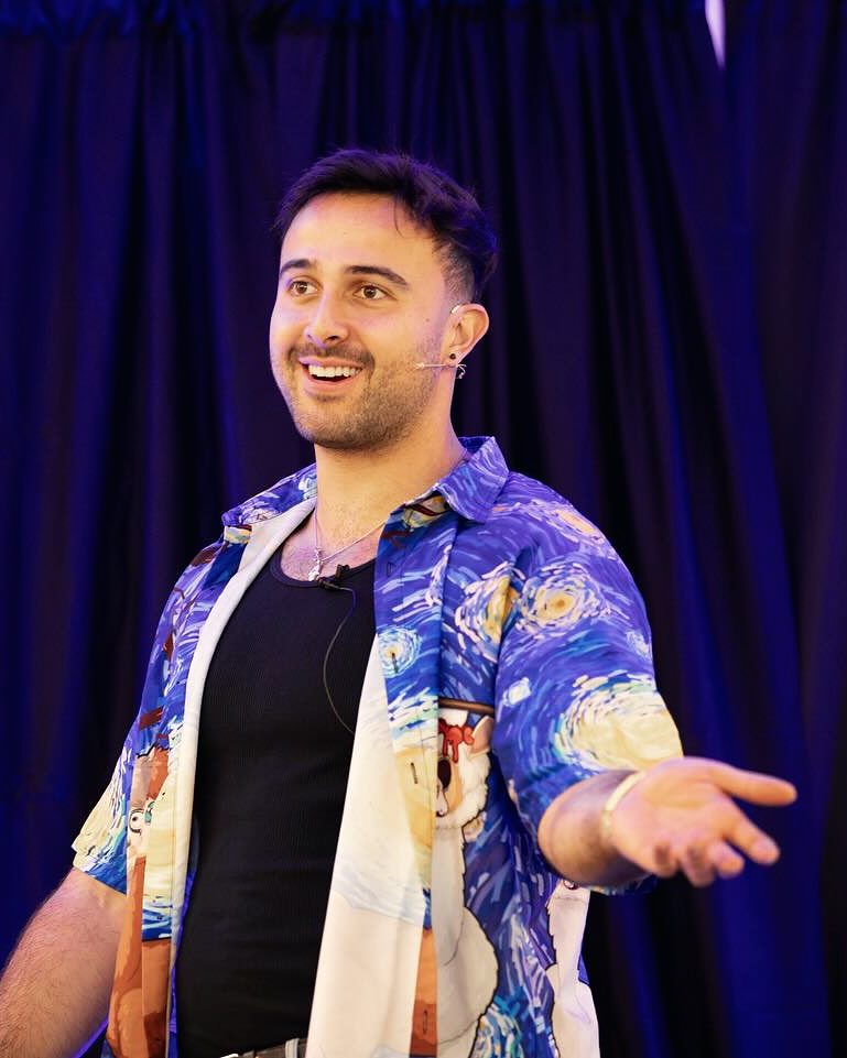 Marczell Klein on stage, smiling, arms open to the audience.