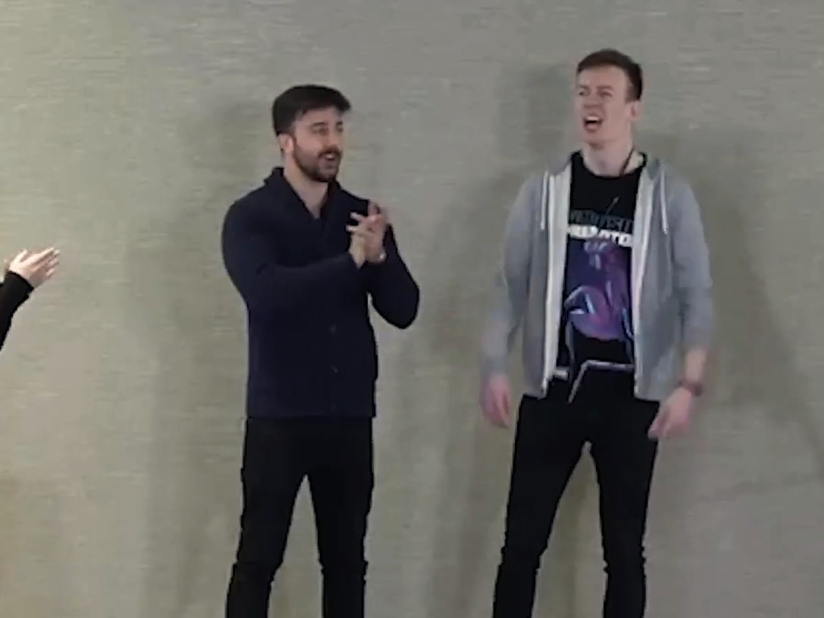 Marczell Klein on stage with a volunteer, both laughing during a live demonstration.