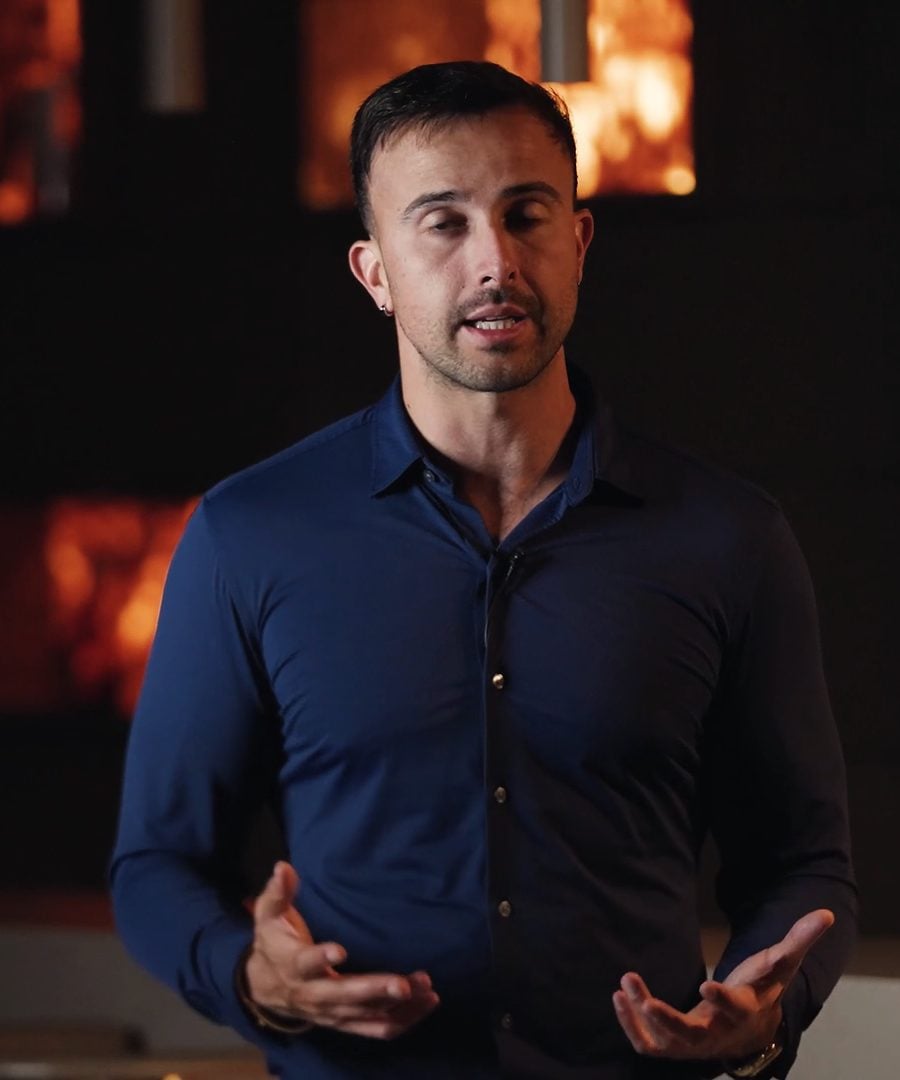 Marczell Klein speaking to camera in front of a warm, softly lit wall.