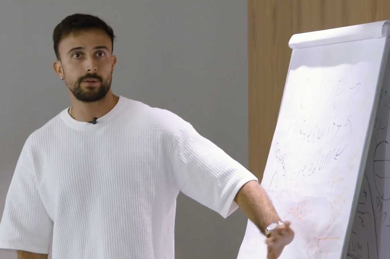 Marczell Klein in a white T-shirt, explaining an idea at a flipchart.